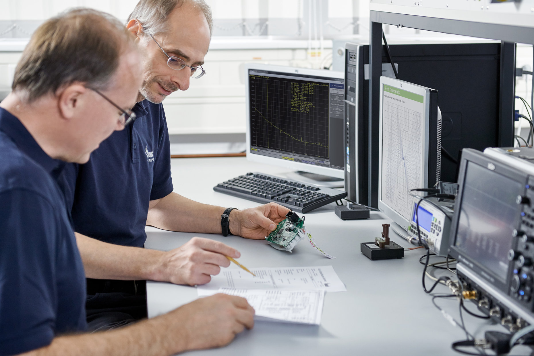 Two men analyze an electronic circuit