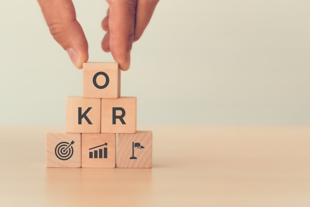 wooden cubes stapled to a pyramid with the letters OKR and three signs