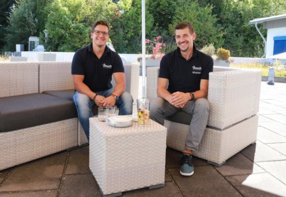 Zwei Männer sitzen bei Sonnenschein auf einer Terrasse